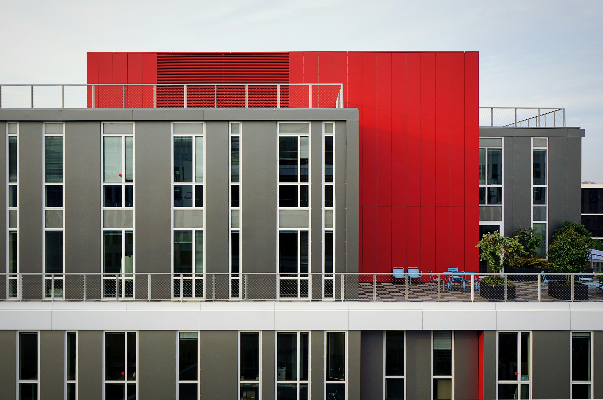 Résidence contemporaine avec façade rouge et grise, idéale pour une gestion locative en LMNP dans un quartier en plein essor