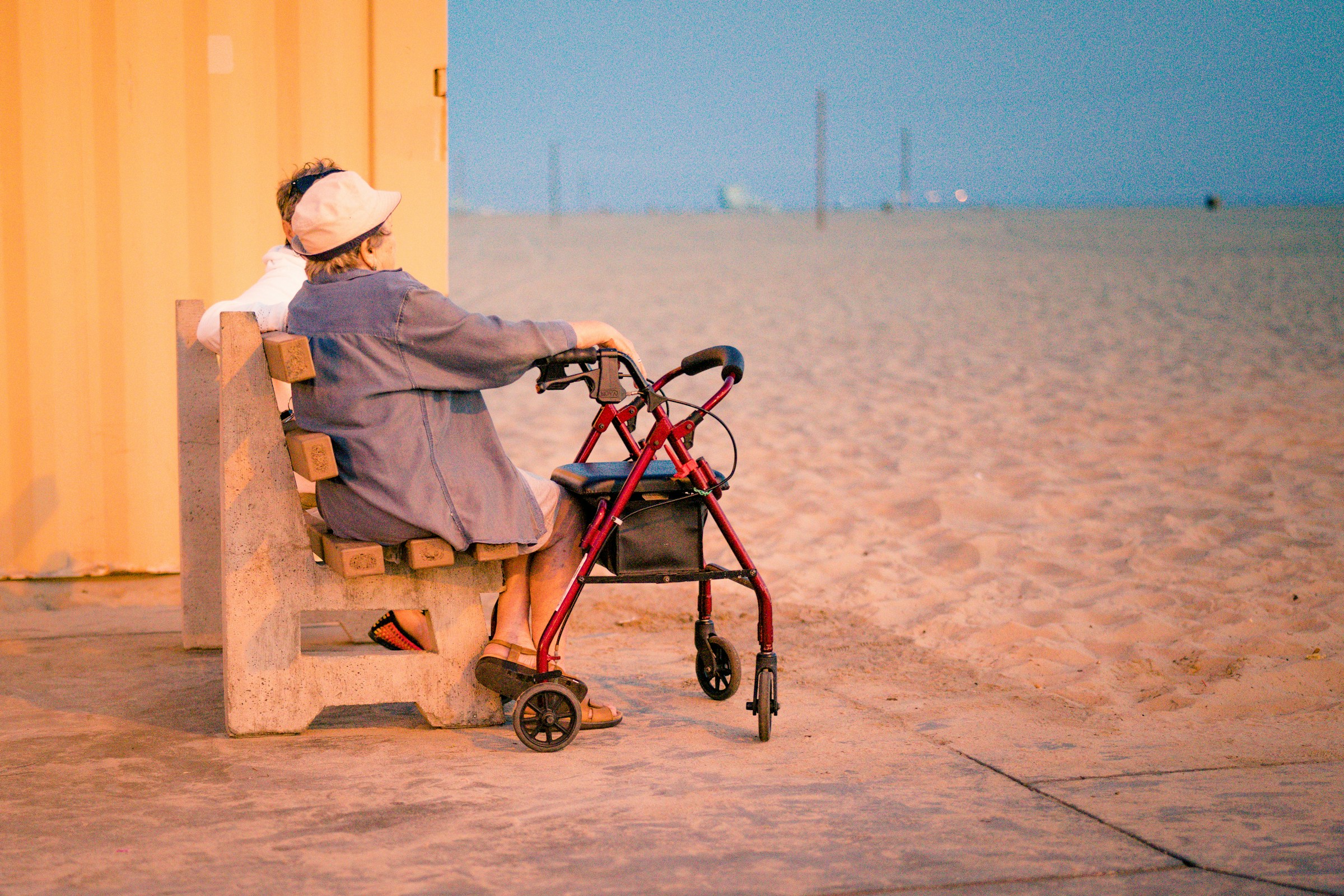 Personnes âgées assises sur un banc à la plage, avec un déambulateur, illustrant les profils résidents visés par les EHPAD en LMNP.