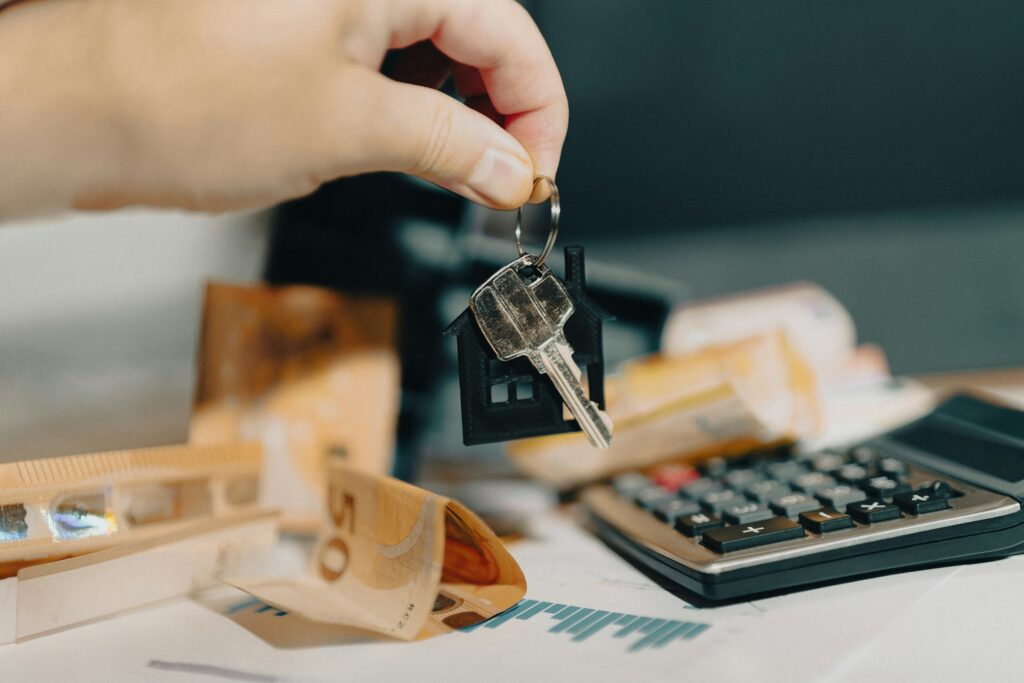 Main tenant une clé immobilière au-dessus de billets d'euros pour illustrer le financement LMNP.