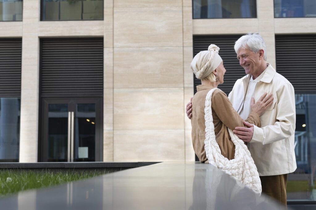 Couple de seniors souriants devant une résidence moderne, illustrant la LMNP résidence senior comme solution d’investissement sécurisée.