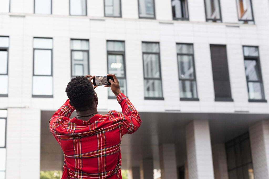 Homme prenant en photo un immeuble dans le cadre d’un projet LMNP en SCI