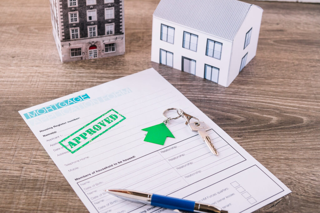 formulaire de prêt immobilier approuvé avec une maquette de maison, illustrant une stratégie d’investissement avec déficit foncier LMNP