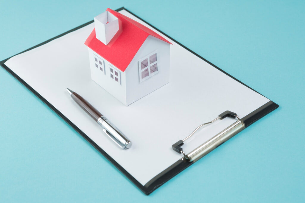 maquette de maison avec stylo sur un dossier vierge, symbolisant une étude fiscale sur le déficit foncier LMNP