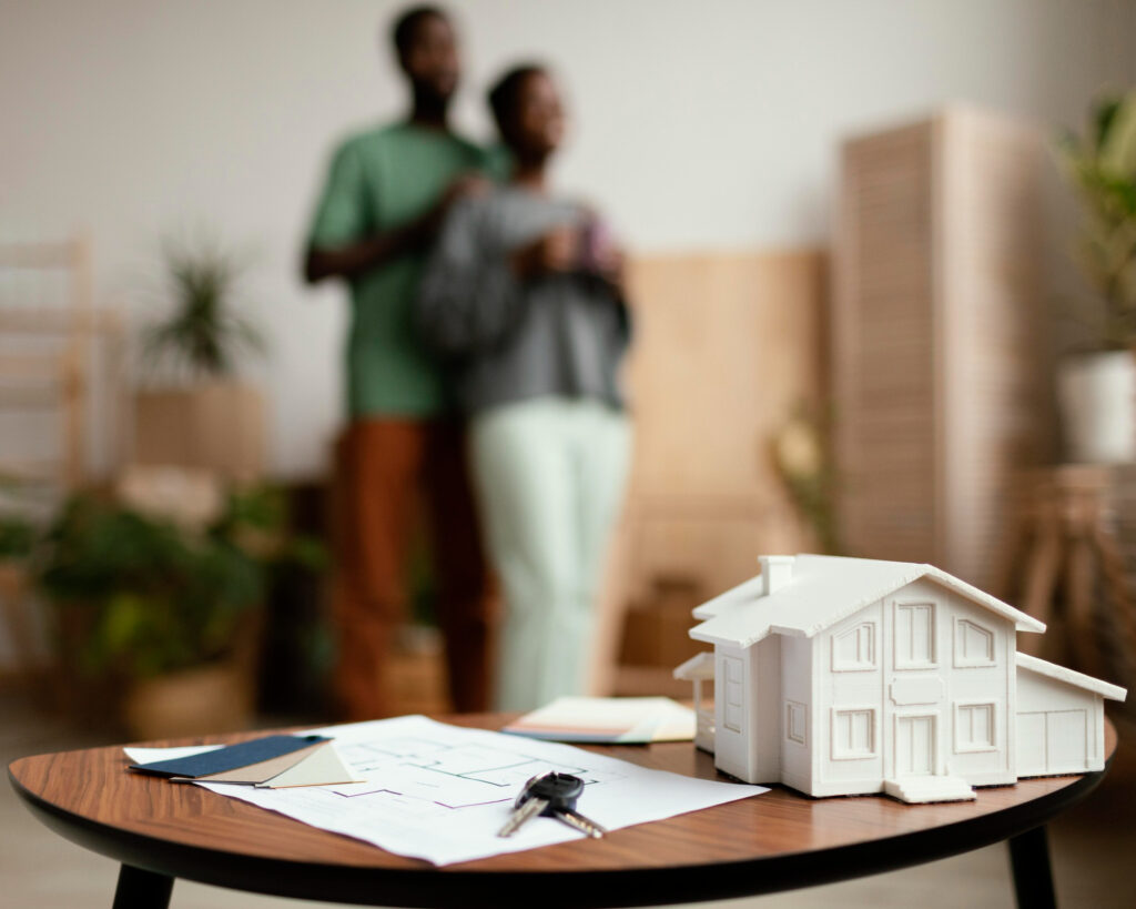 maquette de maison sur table et couple discutant d’un projet de colocation meublée LMNP