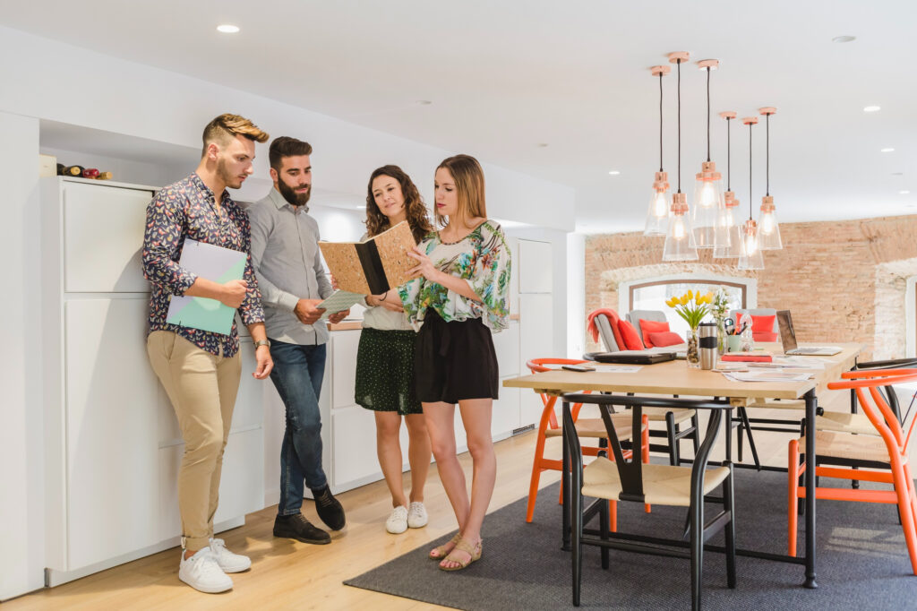 Groupe de jeunes adultes échangeant dans une cuisine moderne, représentant une situation typique d’une colocation étudiée lors d’une simulation LMNP en colocation.