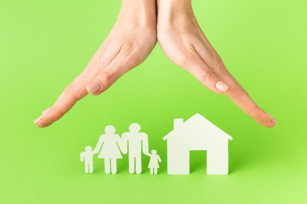 assurance loyers impayés LMNP protégeant une famille et une maison avec des mains protectrices