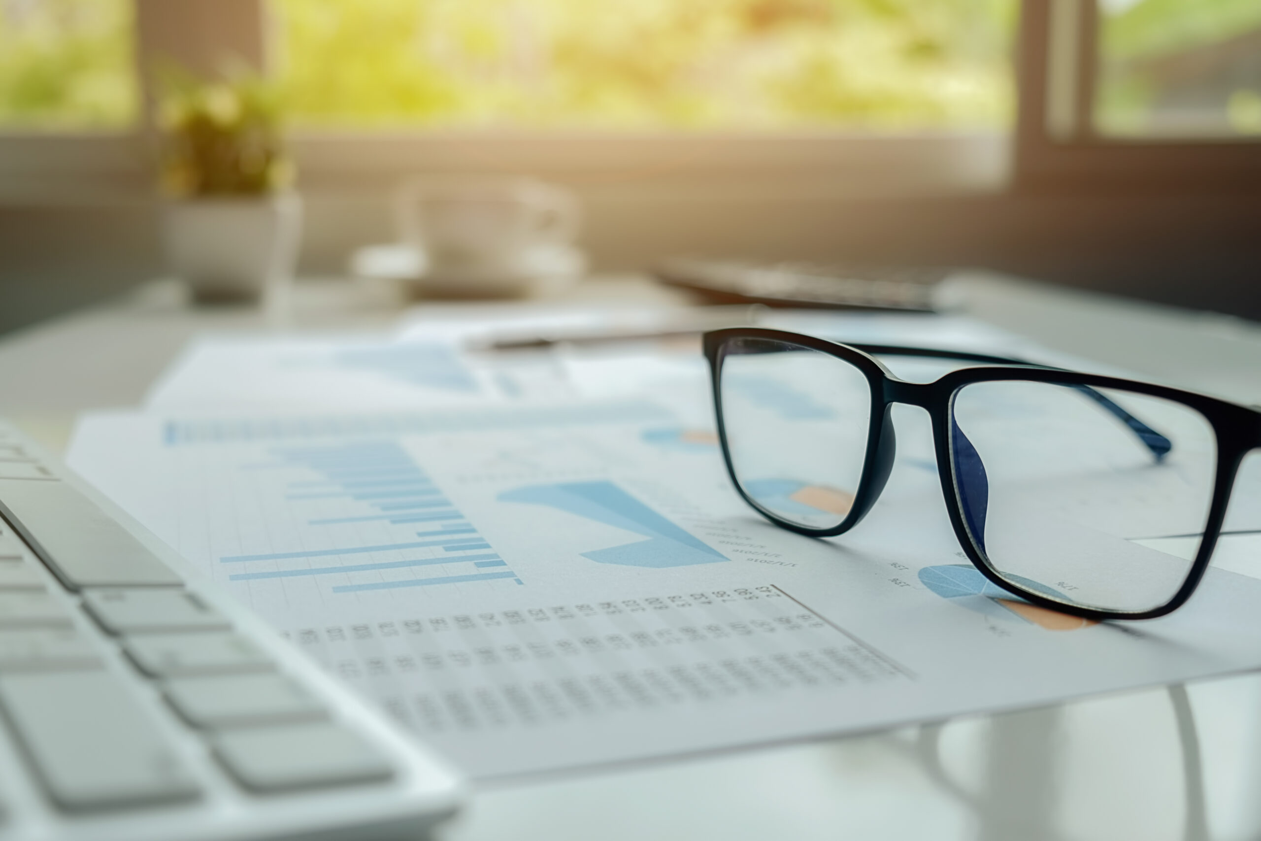Bureau d'analyse de dossier EHPAD : lunettes posées sur un rapport financier, ambiance de travail concentrée